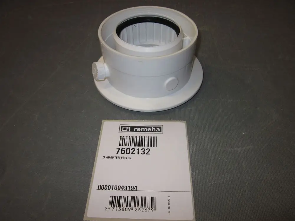Weißer Kunststoffadapter von Remeha mit einer runden Öffnung und seitlichem Anschluss, auf einem grauen Untergrund platziert. Barcodes und Artikelnummer auf dem Etikett sichtbar.